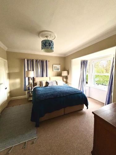 a bedroom with a blue bed and a window at Princeland Lodge in Blairgowrie