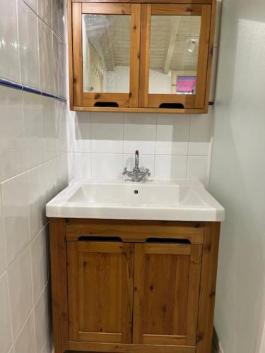 La salle de bains est pourvue d'un lavabo et d'une armoire en bois. dans l'établissement Maison Trinque Dit, à Audenge