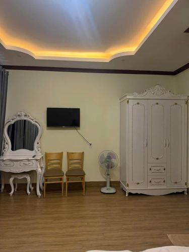 a room with a tv and a white cabinet and chairs at Thảo Nguyên Hotel in Kinh Dinh