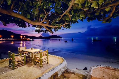 ein Tisch und Stühle am Strand in der Nacht in der Unterkunft VIVA on the Beach Hotel in Chaloklum