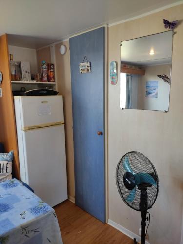 Cette chambre dispose d'une porte bleue et d'un ventilateur. dans l'établissement Mobil home 6 place a 900 mètres de la plage, à Agde