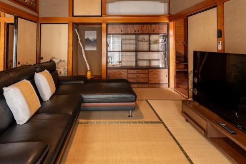 a living room with a leather couch and a flat screen tv at 珈琲好きのための和モダン貸切一軒家 in Iwaki