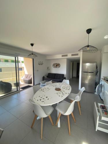 une table blanche et des chaises dans un salon dans l'établissement Le Refuge du Plongeur - Appartement, à Saint-Mandrier-sur-Mer