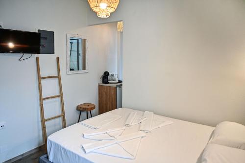 a room with a bed with white sheets and a ladder at Ikaria Studios in Agios Kirykos