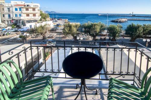 two chairs and a table on a balcony overlooking the water at Ikaria Studios in Agios Kirykos