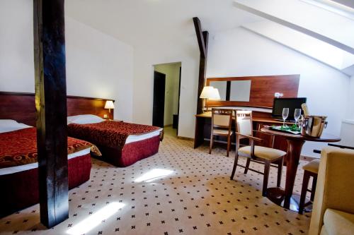 a hotel room with two beds and a desk and a table at Gościniec Uniejów in Uniejow