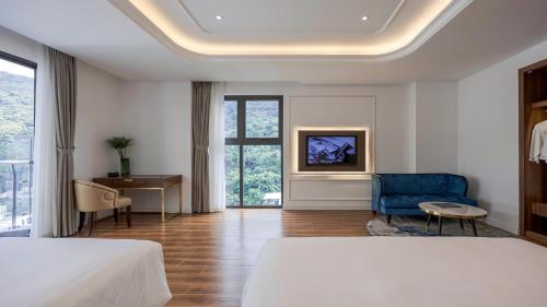 a hotel room with two beds and a blue chair at OYSTER BAY HOTEL VUNG TAU in Vung Tau