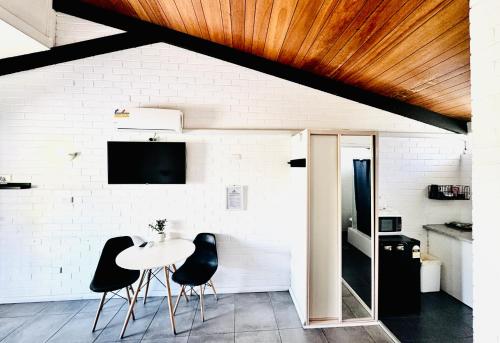 a dining room with a table and black chairs at Jetty Motel The Entrance in The Entrance