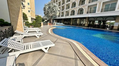 a hotel with a swimming pool and two white benches at LK CRYSTAL Ville Pattaya in Pattaya South