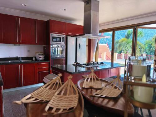 a kitchen with red cabinets and a counter with two tables at Kata Sea Cloud Villa半山海景独栋别墅 in Kata Beach
