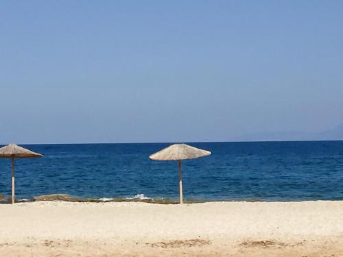 two straw umbrellas on a beach with the ocean at Filio's home in Zárakes