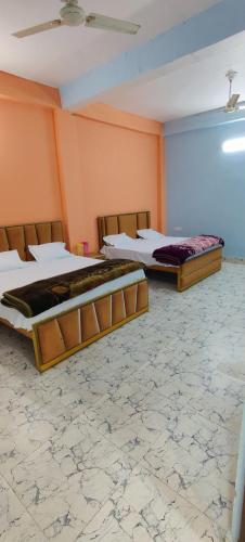 two beds in a room with orange walls at Geetasheel Palace in Naimishāranya