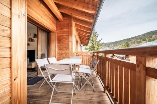 a wooden balcony with a table and chairs on it at Apartment Thredbo, Les Carroz d'Arâches - by EMERALD STAY in Arâches-la-Frasse