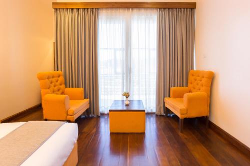 a hotel room with two chairs and a bed and a table at Hotel Grand Turf By GSP in Nuwara Eliya