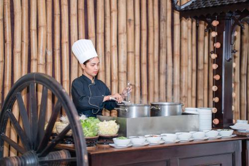 a woman cooking in a kitchen with pots and pans at Khemara Angkor Hotel & Spa in Siem Reap