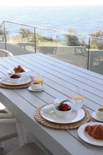 a table with plates of food and drinks on it at Coastal Indulgence Water Views Romantic Coastal Beach Getaway Kiama in Kiama