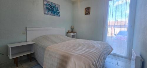 une chambre blanche avec un lit et une fenêtre dans l'établissement Appartement 2 chambres, jardin & parking à Valras, à Valras-Plage