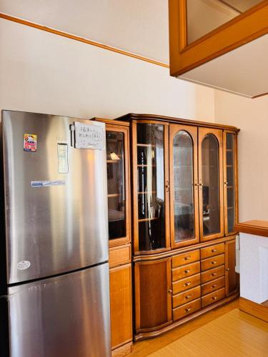 a kitchen with a stainless steel refrigerator and wooden cabinets at 麗静亭 in Koga