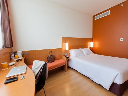 ein Hotelzimmer mit einem Bett und einem Schreibtisch mit einem Laptop in der Unterkunft Ibis Abu Dhabi Gate in Abu Dhabi