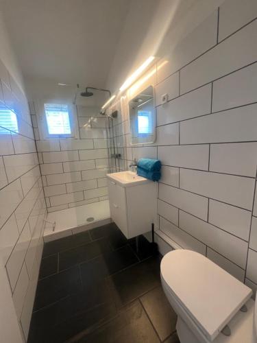 a white bathroom with a toilet and a sink at Lovely studio perfect for couples close to beach in Moliets-et-Maa