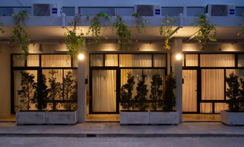 a facade of a building with glass doors and plants at Dear Sunday Hometel Bangkok in Bangkok