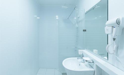 Un baño blanco con lavabo y espejo. en RedDoorz Premium at Regency Sunset Hotel, en Ángeles