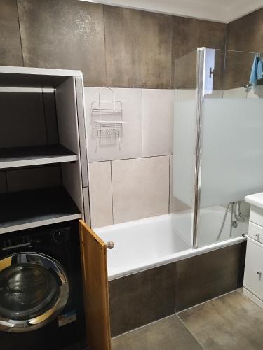une salle de bain avec un lave-linge et une baignoire dans l'établissement Chez Monique et Dédé, à Ferrassières