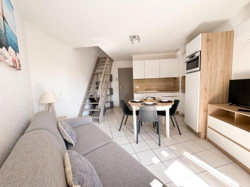 a living room with a couch and a table and a kitchen at Malibu Village in Canet-en-Roussillon