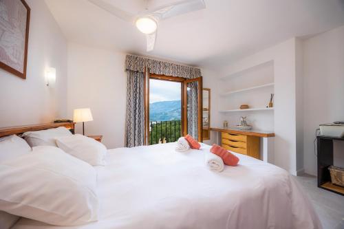 a bedroom with a large white bed with a window at Villa Carla in Port de Soller