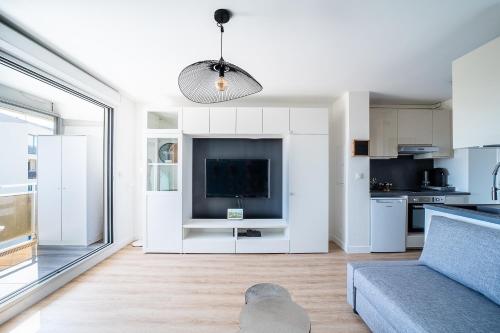 un salon avec un canapé et une télévision dans l'établissement L’Écrin du Roussillon - Studio proche mer, à Canet