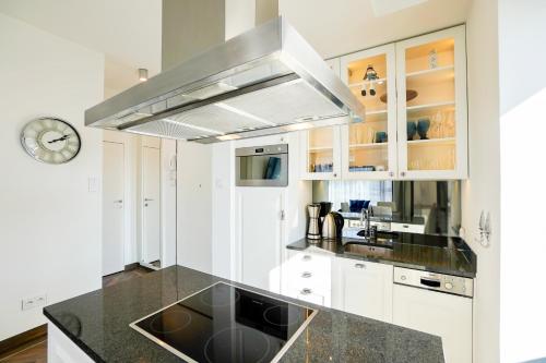 a kitchen with white cabinets and a black counter top at Baltic Park Plaza by Baltic Home in Świnoujście