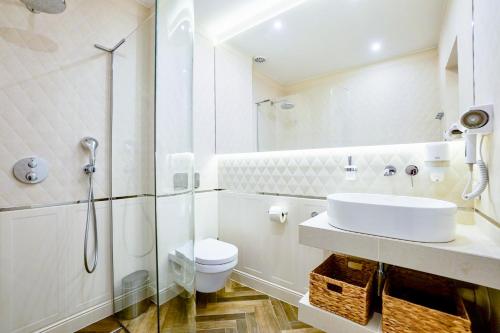 a white bathroom with a sink and a toilet at Baltic Park Plaza by Baltic Home in Świnoujście