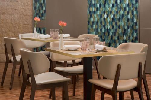 a dining room with tables and chairs with vases at NH Palermo in Palermo