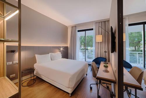 a hotel room with a white bed and a desk at NH Palermo in Palermo