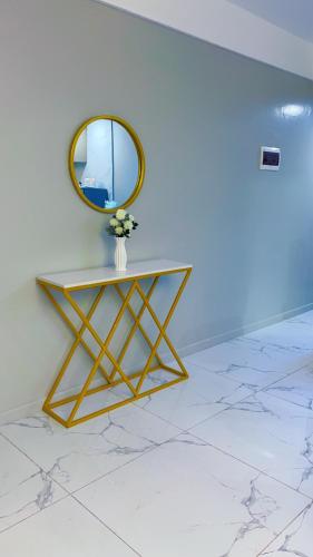 a table with a mirror and a vase with flowers at Caster two bedrooms apartment jkia in Nairobi
