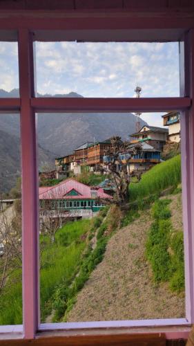 GushainiにあるGyani Homestay - Tirthanの山からの町の景色を望む窓