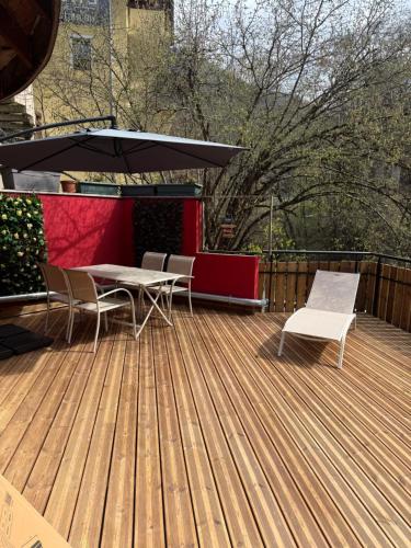 eine Terrasse mit Tisch und Stühlen und einem Sonnenschirm in der Unterkunft Nouveau T3 RDC 100m du parc in Brides-les-Bains