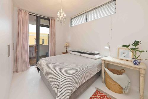 a bedroom with a bed and a table and a window at Muizenberg Apartment in Muizenberg