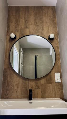 y baño con espejo grande sobre bañera. en Mikroapartamenty Garden, en Oleśnica