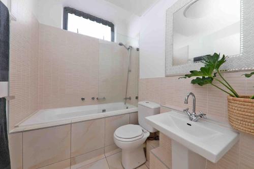 a bathroom with a toilet and a sink and a bath tub at Muizenberg Apartment in Muizenberg