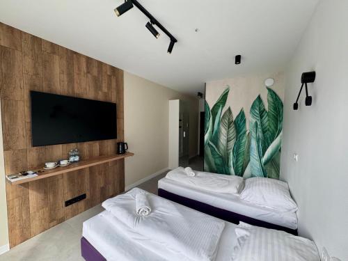 a room with two beds and a flat screen tv at Mikroapartamenty Garden in Oleśnica
