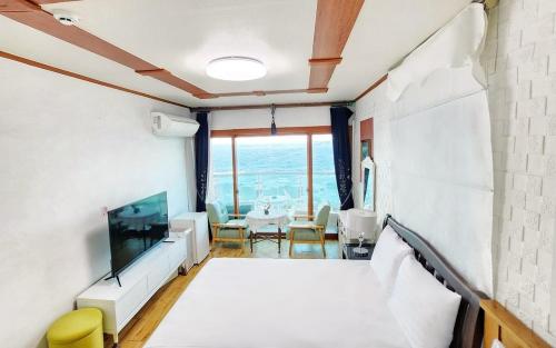 a room with a bed and a tv and a table at Jeju Yongdam House in Jeju