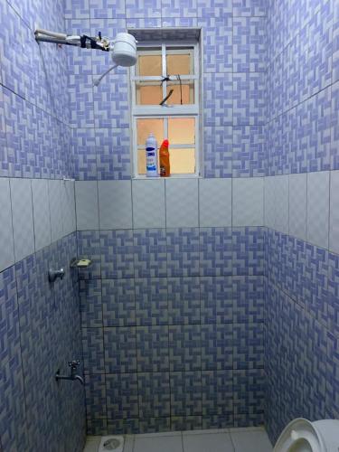 a blue tiled bathroom with a window and a toilet at Angie's Paradise in Syokimau
