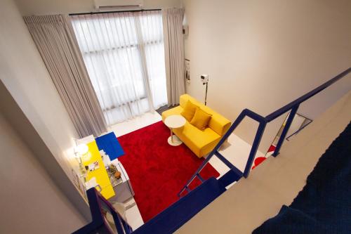 a living room with a yellow couch and a red rug at Dear Sunday Hometel Bangkok in Bangkok