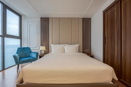 a bedroom with a large bed and a blue chair at OYSTER BAY HOTEL VUNG TAU in Vung Tau