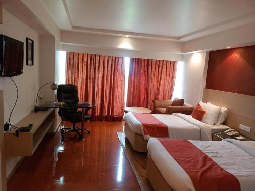 a hotel room with two beds and a desk at Hotel Amer Green's in Bhopal
