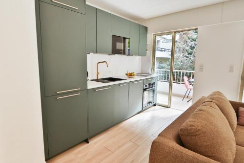 - une cuisine avec des placards verts et un canapé dans l'établissement Spacieux T2 avec grande terrasse à 200m de la plage, à Cannes