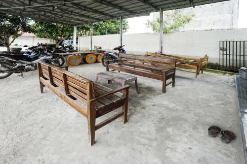 three wooden benches sitting under a tent with motorcycles at Hotel O Penginapan Indah Permai Syariah in Tanjungraya