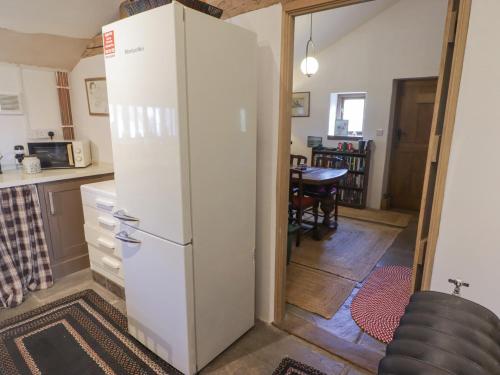 a white refrigerator in a kitchen with a table at Tipyn Bach in Caerphilly
