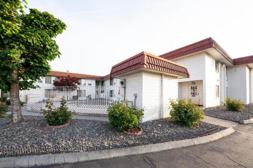 a white building with a fence in front of it at OYO Hotel Hermiston OR, Downtown in Hermiston